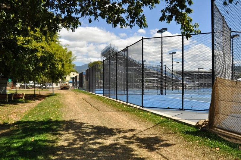 Chain wire court enclosure beside a shaded path