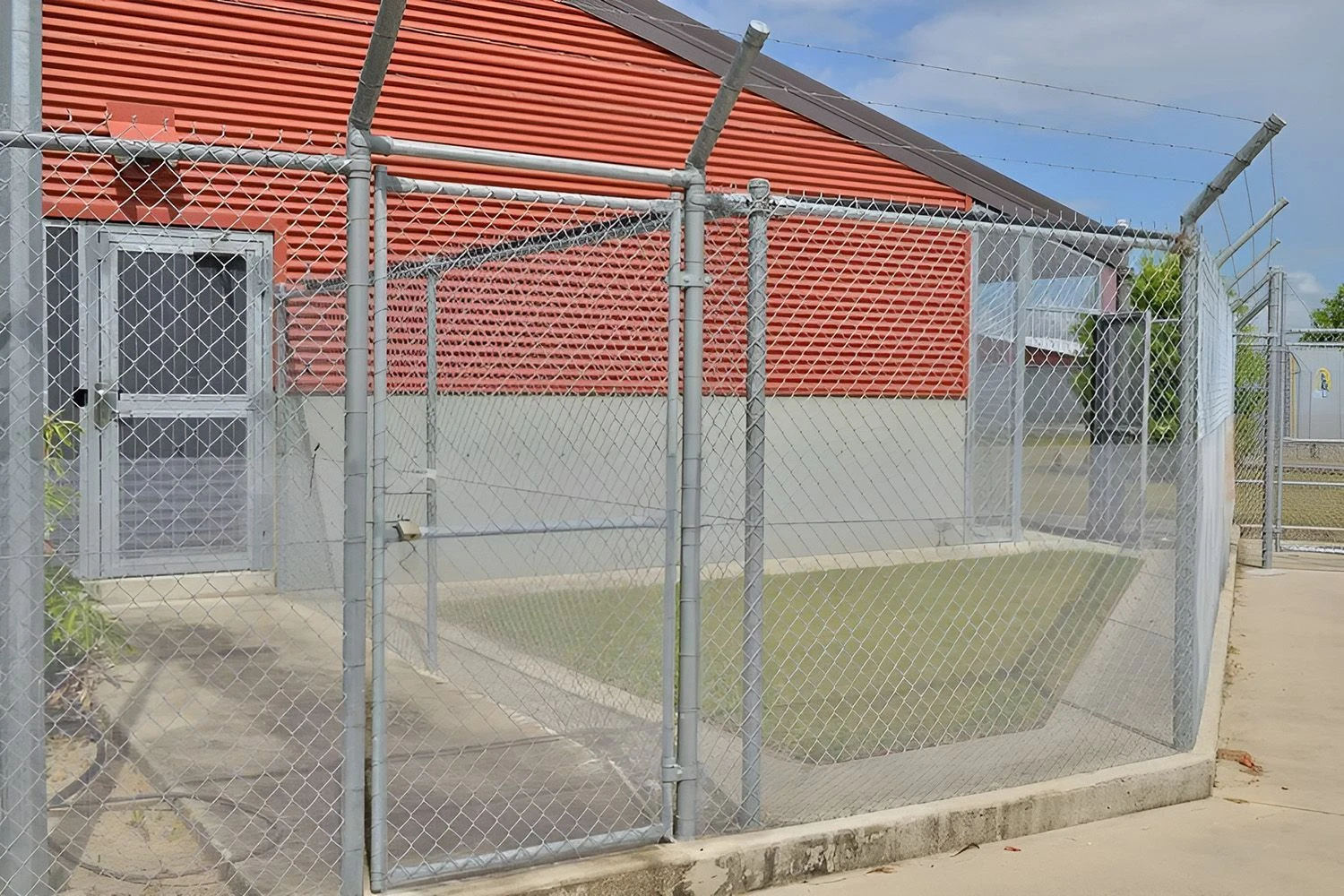 Galvanised chain wire enclosure built against a brick building